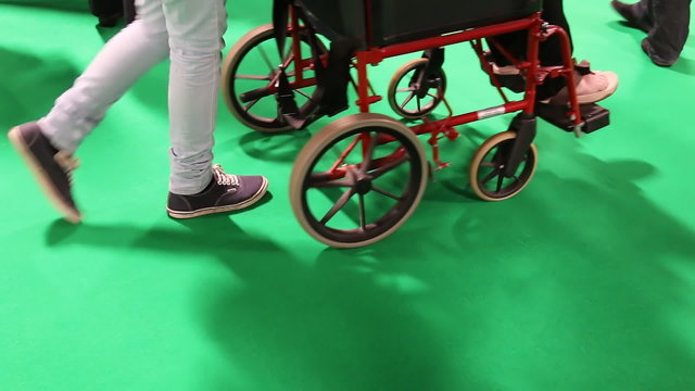 People, caretaker pushing wheelchair on green background