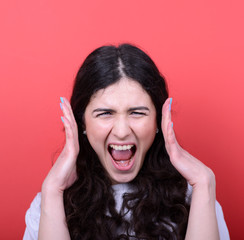 Portrait of angry girl screaming against red background