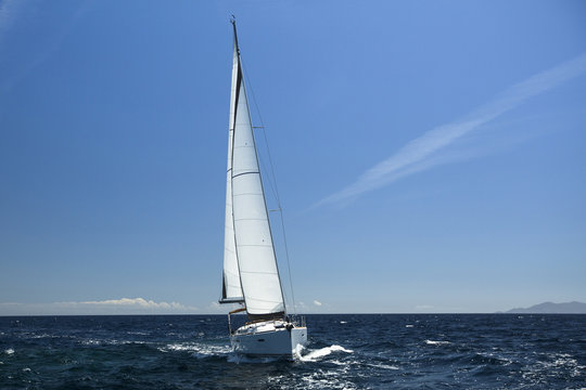 Sailing ship yachts with white sails in open sea.