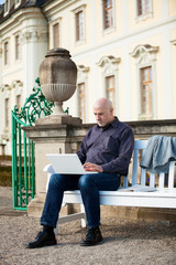 Man sitting on a bench using a laptop