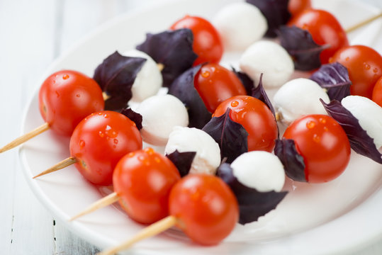 Cherry tomatoes, basil leaves and mozzarella balls on skewers