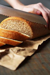Female hands cutting bread on wooden board, close-up