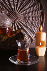 Tea pouring into glass cup on dark background