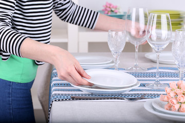 Woman laying table in room