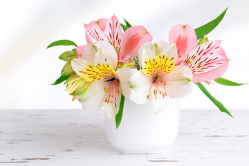Alstroemeria flowers in vase on table on light background