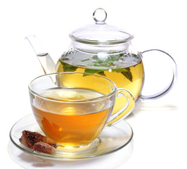 Composition of fresh mint tea in glass cup and teapot and brown