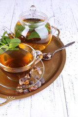 Composition of fresh mint tea in glass cup and teapot