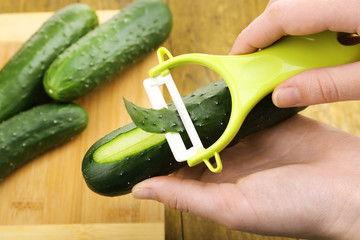 Hands peeling cucumber close up