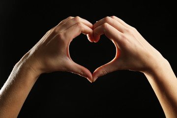 Human hands making heart on black background