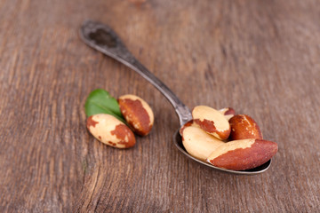 Vintage spoon with tasty brasil nuts on wooden background