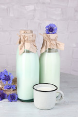 Fototapeta na wymiar Bottles and cup of milk with cornflowers on wooden table