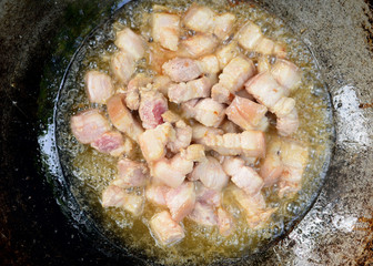 Three pork belly slices on a black pan