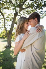 Fototapeta premium Smiling young couple embracing in park