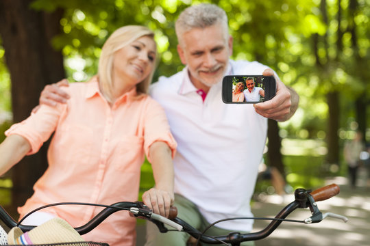 Loving mature couple taking selfie by mobile phone