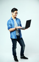cheerful asian man using laptop on gray background