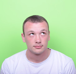 Fototapeta premium Portrait of man thinking and looking up against green background