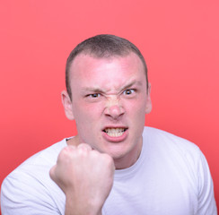 Portrait of angry man screaming showing fist against red backgro
