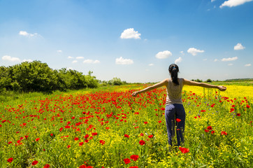 Young woman relaxing in a poppy field