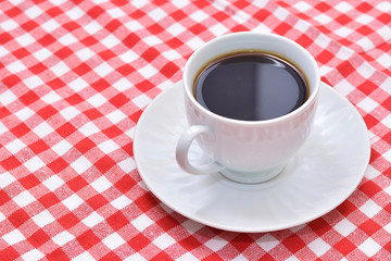 A cup of coffee on picnic blanket.