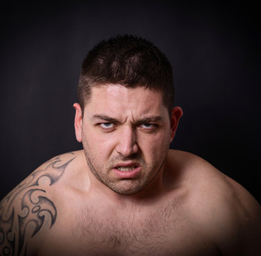 Portrait of angry man against dark background