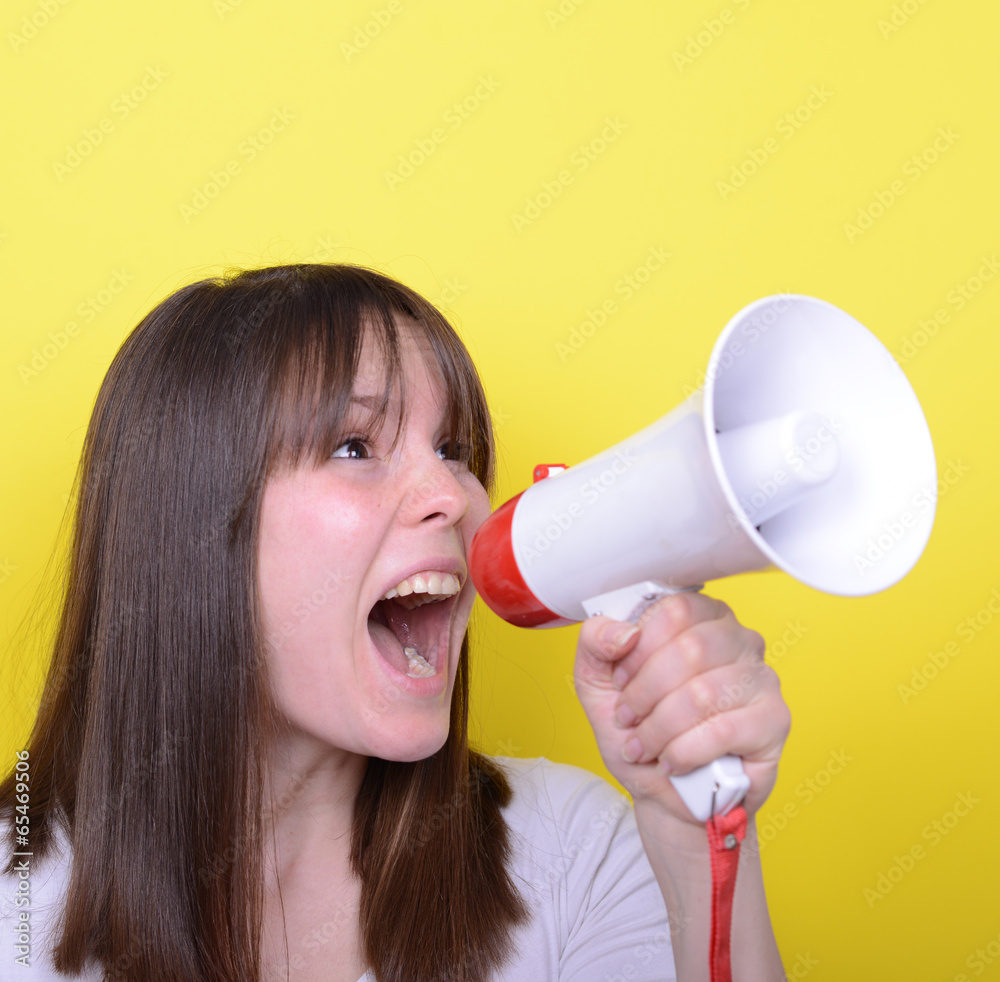 Wall mural portrait of young woman shouting with a megaphone against yellow