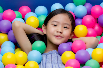 Happy Asian child playing at kindergarten with colorful balls