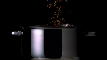 Popcorn kernels falling into pot on black background - Powered by Adobe