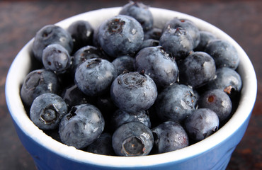 Blueberries in blue bowl on brown background