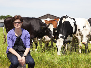 Woman sitting on milk jug in front of the cows