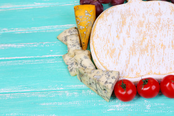 Different types of cheese with empty board on table close-up