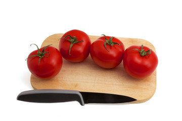 Tomaten mit Messer auf kleinem Holzbrett