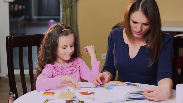 Happy mother teaches little daughter color book, learning colors