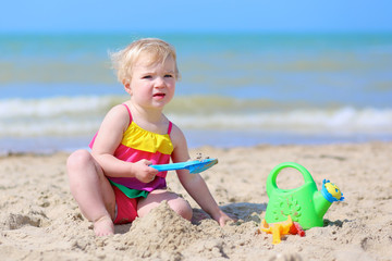 Happy little girl building sand castles on the beach