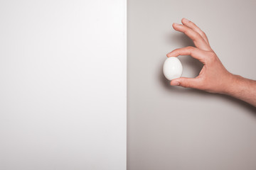 Fototapeta na wymiar Hand holding an egg against a dual colored background