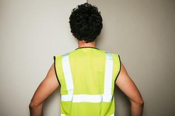 Rear view of builder in high visibility vest - 65494180