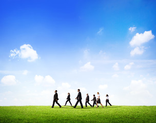 Group Of Business People Walking Through The Field In Daylight