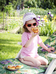 Little girl eating cake in the garden - obrazy, fototapety, plakaty