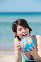 attraktive junge frau mit globus am strand