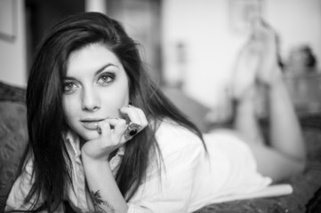 Sensual portrait of beautiful girl with tattoo lying on sofa. Bl