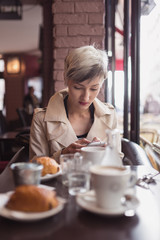 Young woman sending message with cellular phone in a cafe in Par