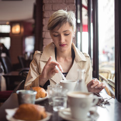 Young woman drinking coffee in a cafe in Paris, France. Shallow
