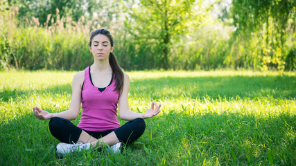 Naklejka na ściany i meble Young woman portrait practicing yoga outdoors in a park.