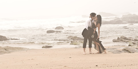 Young attractive couple kissing on beach through the mist