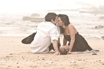 Young attractive couple kissing on beach in the mist