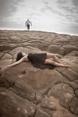 Romantic couple sharing a moment on beach rocks