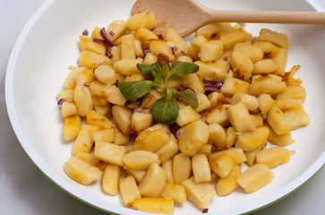 Gnocchi on the frying pan with wooden spoon.