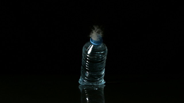Plastic bottle falling and spilling on black surface - Powered by Adobe