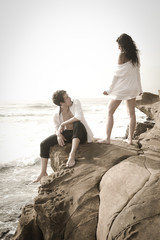 Young good looking couple on beach rocks wearing white