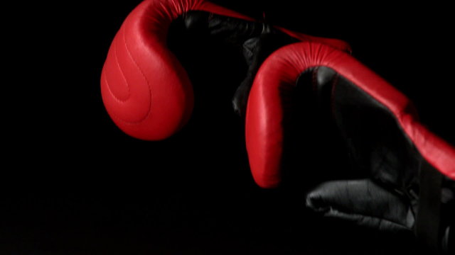 Red boxing gloves falling on black background
