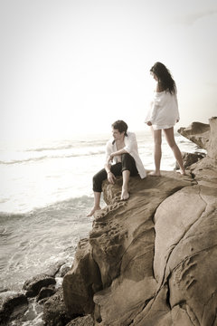 Young good looking couple on beach rocks wearing white